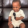 Dale is registered to the contest to win money with this photo: toddler, child, smiling, happy, sunglasses, white_clothing, leather_couch, indoor, person, baby, seated, cute, small_child, playful, portrait, one_person, skin, hand, face, casual