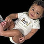 baby, child, onesie, smile, face, foot, hand, animal_print, text_on_clothing, cute, infant, skin, black_background, happy, portrait, sitting, young_child, diaper, playful, casual_clothing