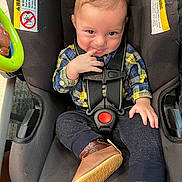 Dallas joined the competition — help win amazing prizes! baby, child, car_seat, plaid_shirt, blue_eyes, brown_hair, finger_in_mouth, booties, smile, cute, infant, seatbelt, clothing, indoor, child_safety, toddler, playful, person, portrait, seat