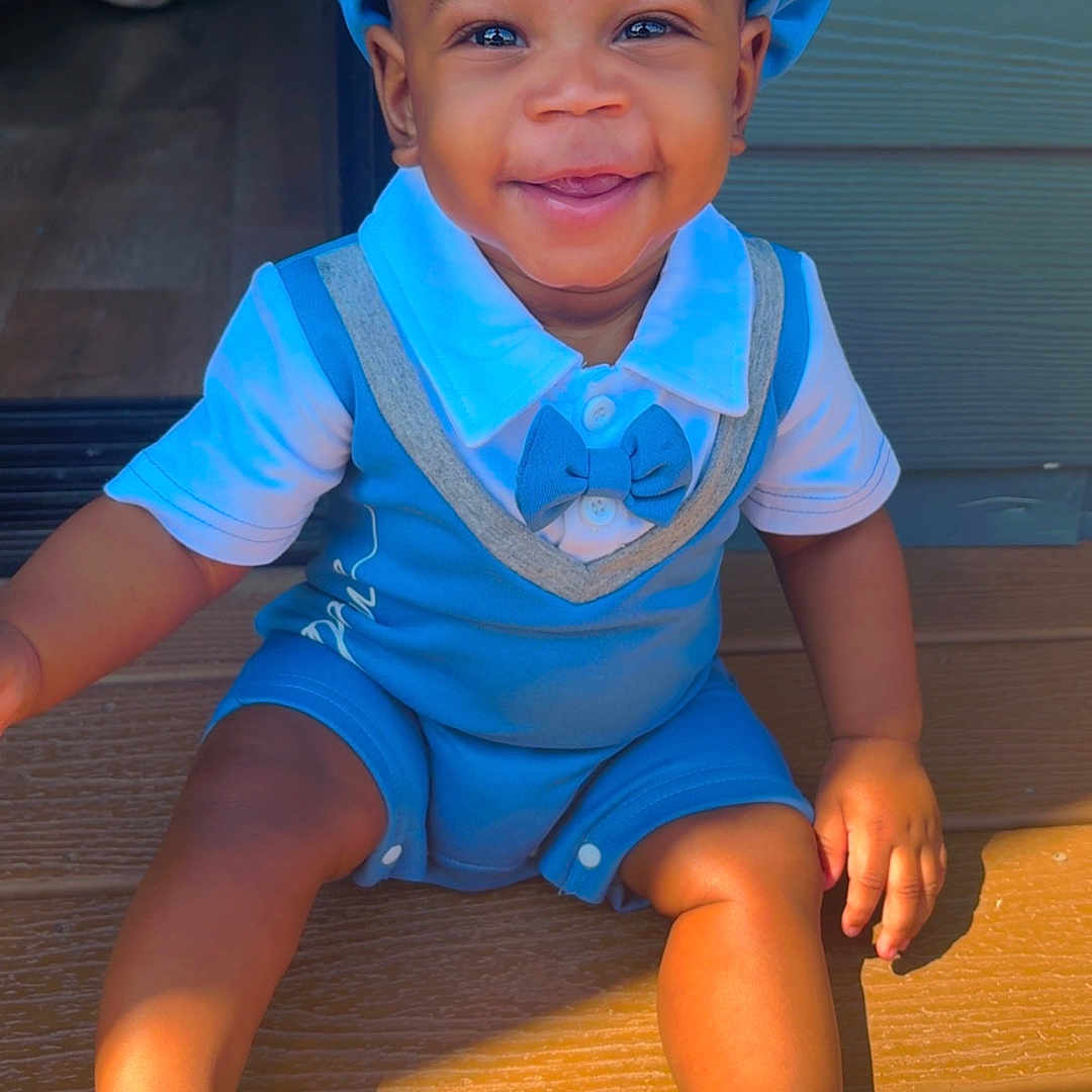 River joined the competition — help win amazing prizes! toddler, child, smiling, blue_outfit, hat, sandals, sunlight, wooden_deck, happy, cute, portrait, baby, outdoor, sitting, footwear, person, summer, playful, bright, casual