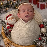 Joyce a rejoint le concours — aidez-le/la à gagner de superbes lots ! newborn, baby, sleeping, basket, christmas, holiday, santa_doll, pinecones, ornaments, knit_blanket, swaddled, festive, decorations, winter, cozy, cute, headband, face, portrait, indoor