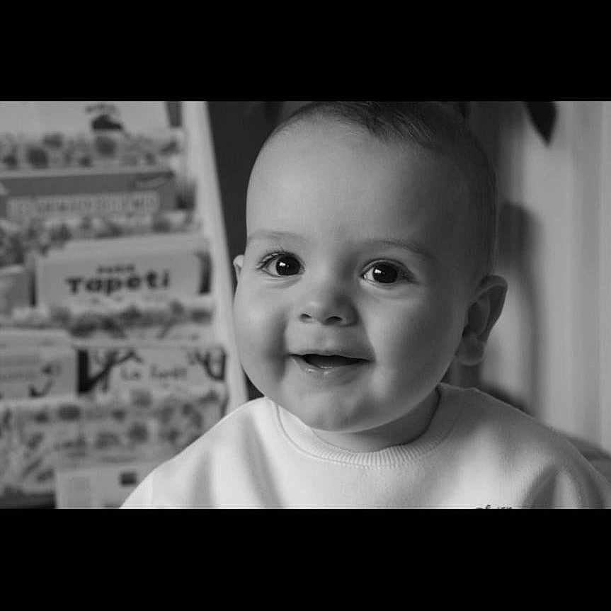 Ezio participe au concours pour gagner de l'argent avec cette photo : baby, background, black_and_white, books, bookshelf, child, close_up, cute, expression, eyes, face, happy, head, indoor, infant, person, portrait, shirt, smiling, young_child