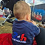 Ezio participe au concours pour gagner de l'argent avec cette photo : 24h_le_mans, back_view, blue_shirt, blurred_background, casual_clothing, child, cloudy_sky, daylight, event, grass, logo, outdoor, people, person, red_blanket, sitting, stroller, toddler, toy, young_child
