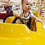 Ezio a rejoint le concours — aidez-le/la à gagner de superbes lots ! baby, child, clothing, excitement, expression, face, hand, head, indoor, kid, mannequin, person, retail, seat, shopping_mall, steering_wheel, store, surprise, toy_car, yellow