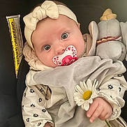 Julia a rejoint le concours — aidez-le/la à gagner de superbes lots ! baby, infant, pacifier, headband, bow, flower, daisy, plush_toy, clothing, blanket, cute, child, soft_toy, portrait, indoor, closeup, hand, face, eyes, baby_clothes