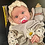 baby, infant, pacifier, headband, bow, flower, daisy, plush_toy, clothing, blanket, cute, child, soft_toy, portrait, indoor, closeup, hand, face, eyes, baby_clothes