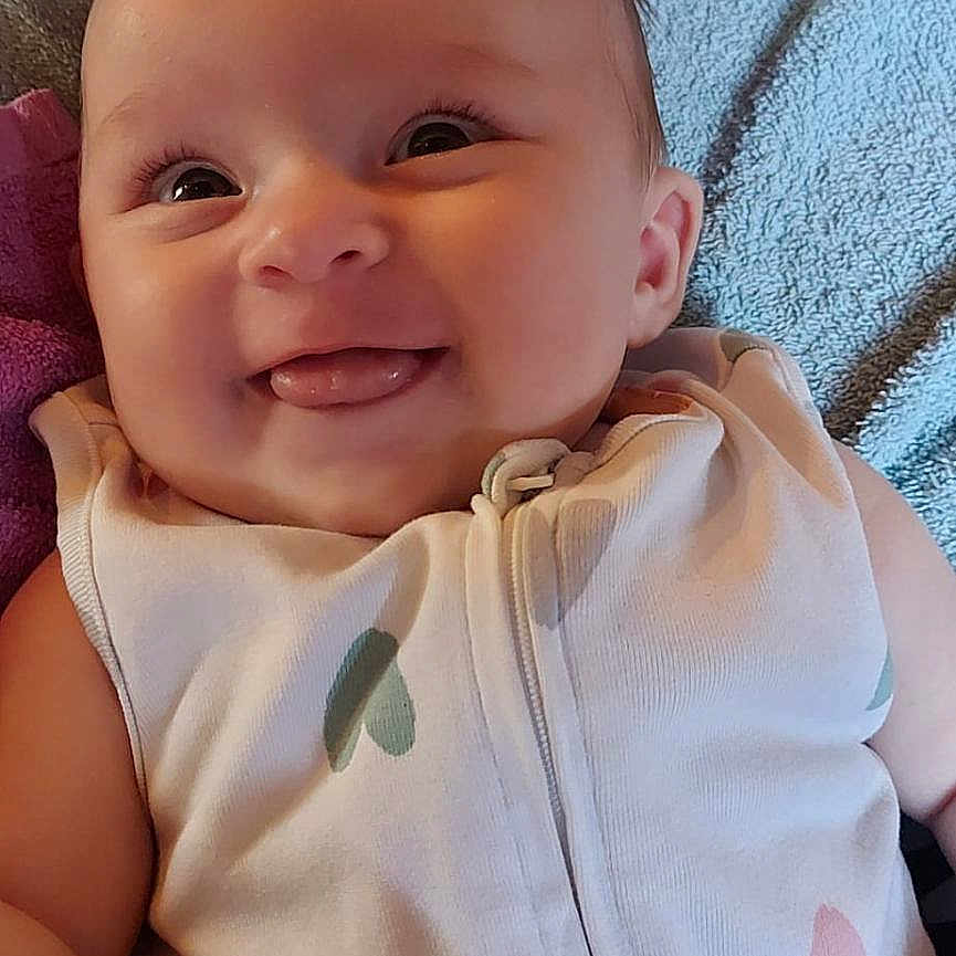Eleanore participe au concours pour gagner de l'argent avec cette photo : baby, blanket, child, closeup, clothing, comfort, cute, expression, fabric, face, happy, head, indoors, infant, lying_down, person, skin, smile, soft, tongue_out