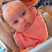 Eleanore a rejoint le concours — aidez-le/la à gagner de superbes lots ! baby, bib, high_chair, towel, face, child, indoor, curious, pink, clothing, feeding, person, infant, cute, head, seat, expression, skin, baby_food, table