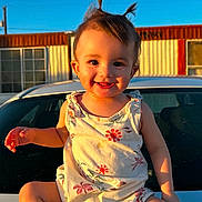 Chelsea joined the competition — help win amazing prizes! toddler, child, smiling, portrait, outdoor, sunlight, car, vehicle, parking_lot, building, blue_sky, hair, dress, floral_pattern, sitting, barefoot, happy, daylight, architecture, photography