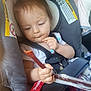 toddler, child, car_seat, seat_belt, snack, food, hand, clothing, hair, face, safety_warning, interior, vehicle, seat, baby, person, closeup, curious, casual, plastic_wrapper