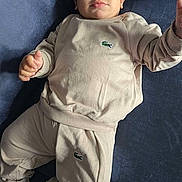 Ilyas participe au concours pour gagner de l'argent avec cette photo : baby, child, infant, clothing, tracksuit, socks, face, person, lying_down, indoor, soft_lighting, portrait, cute, young_child, skin, head, hand, footwear, fabric, logo