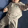 baby, child, infant, clothing, tracksuit, socks, face, person, lying_down, indoor, soft_lighting, portrait, cute, young_child, skin, head, hand, footwear, fabric, logo