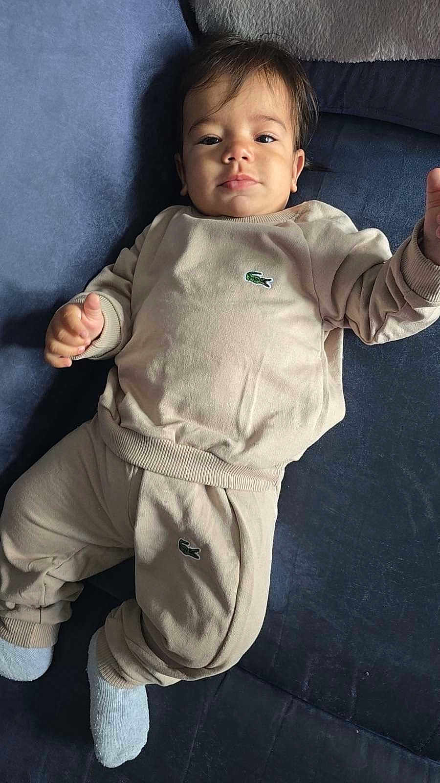 Ilyas participe au concours pour gagner de l'argent avec cette photo : baby, child, infant, clothing, tracksuit, socks, face, person, lying_down, indoor, soft_lighting, portrait, cute, young_child, skin, head, hand, footwear, fabric, logo