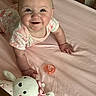 baby, bed, child, crib, cute, face, foot, hand, happy, indoor, infant, light, onesie, pacifier, person, pink_sheet, plush_toy, smiling, soft, toy