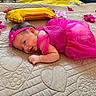 baby, newborn, child, infant, portrait, pink_dress, headband, flower, balloon, gold_balloon, quilt, bed, lying_down, smiling, face, eyes, hands, indoor, celebration, colorful
