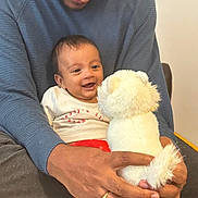 Thiyansh Jaswik is registered to the contest to win money with this photo: baby, adult, smile, stuffed_animal, toy, hands, clothing, sitting, indoor, blanket, happy, face, person, cuddle, warmth, family, bonding, casual, comfort, love