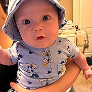 Westin joined the competition — help win amazing prizes! baby, child, mickey_mouse, hat, bucket_hat, onesie, clothing, person, indoor, curious, wide_eyes, cute, infant, holding, hand, face, portrait, closeup, room, carpet