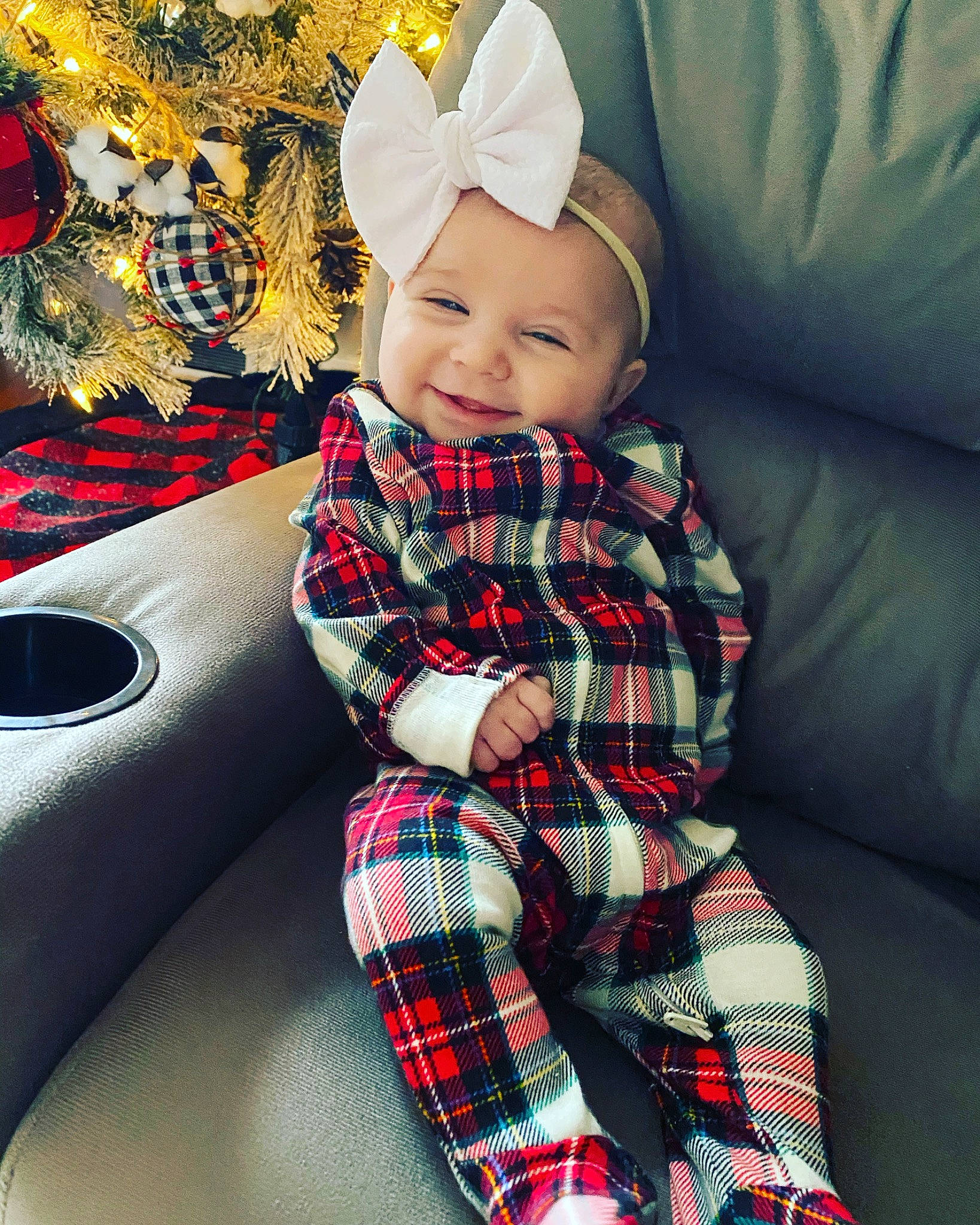 Laney is registered to the contest to win money with this photo: baby, baby_toddler_clothing, bonnet, child, comfort, costume_accessory, costume_hat, couch, design, happy, headgear, headwear, living_room, mouth, nose, pattern, person, plaid, sock, tartan