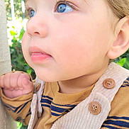 Beckham is registered to the contest to win money with this photo: toddler, child, face, blue_eyes, close_up, outdoor, curious, portrait, soft_lighting, skin, clothing, button, hand, long_eyelashes, nature, greenery, young_child, casual_wear, daylight, expression