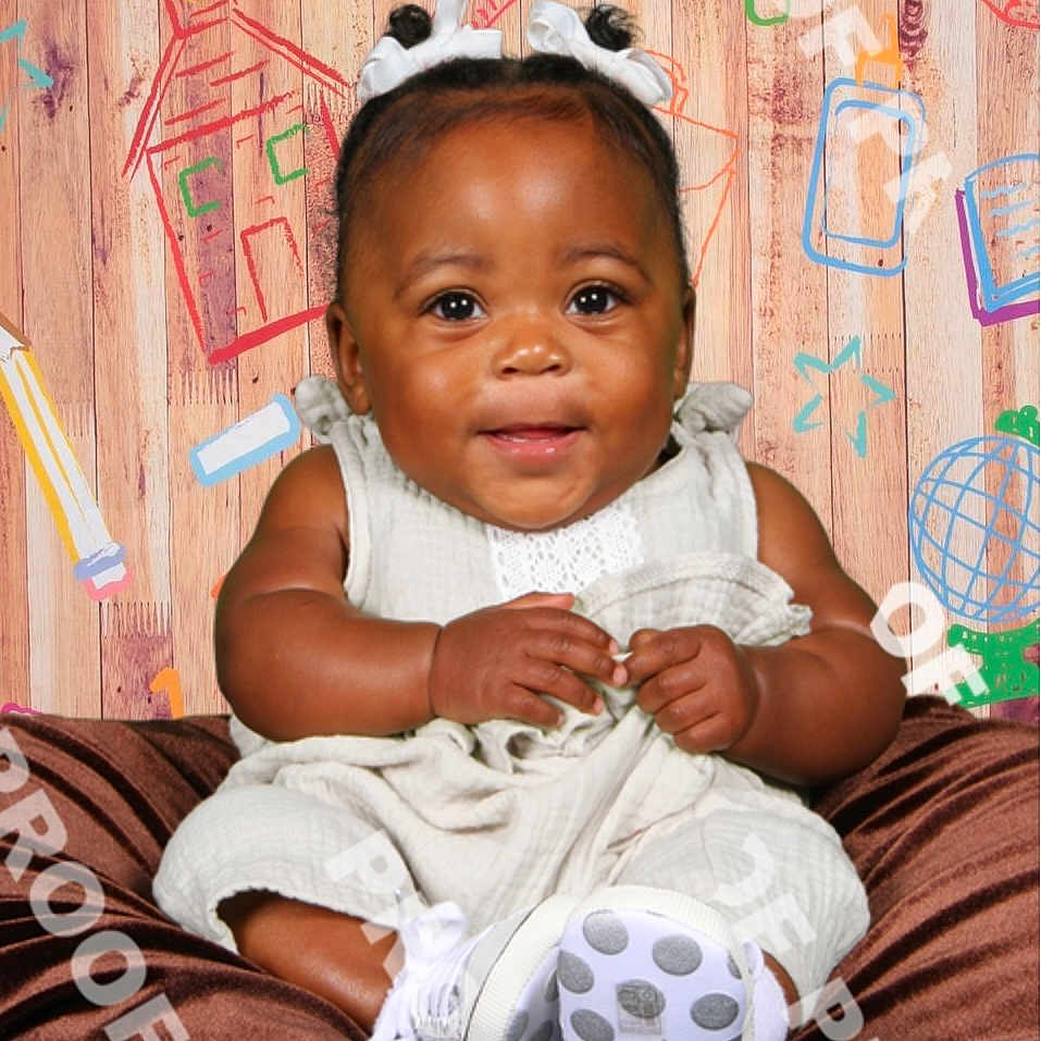 Amora is registered to the contest to win money with this photo: accessories, baby, bodypart, clothing, dress, face, finger, footwear, glove, hand, happy, hat, head, jewelry, person, photography, portrait, shoe, sitting, wood