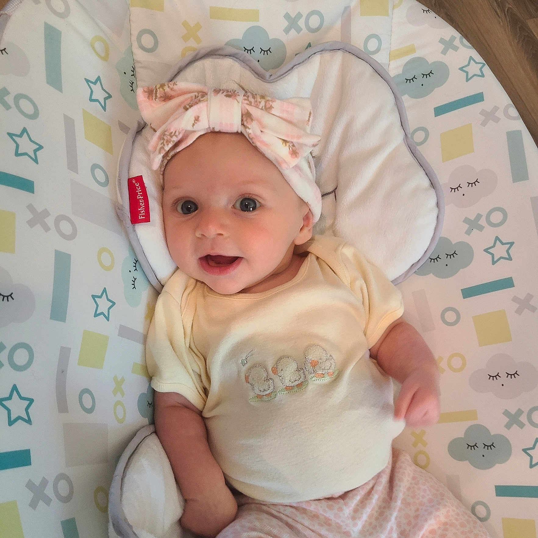 Penelope is registered to the contest to win money with this photo: baby, infant, headband, pink, yellow, patterned, clothing, seat, cute, smiling, face, eyes, hand, fabric, comfort, indoors, child, pastel_colors, apparel, resting