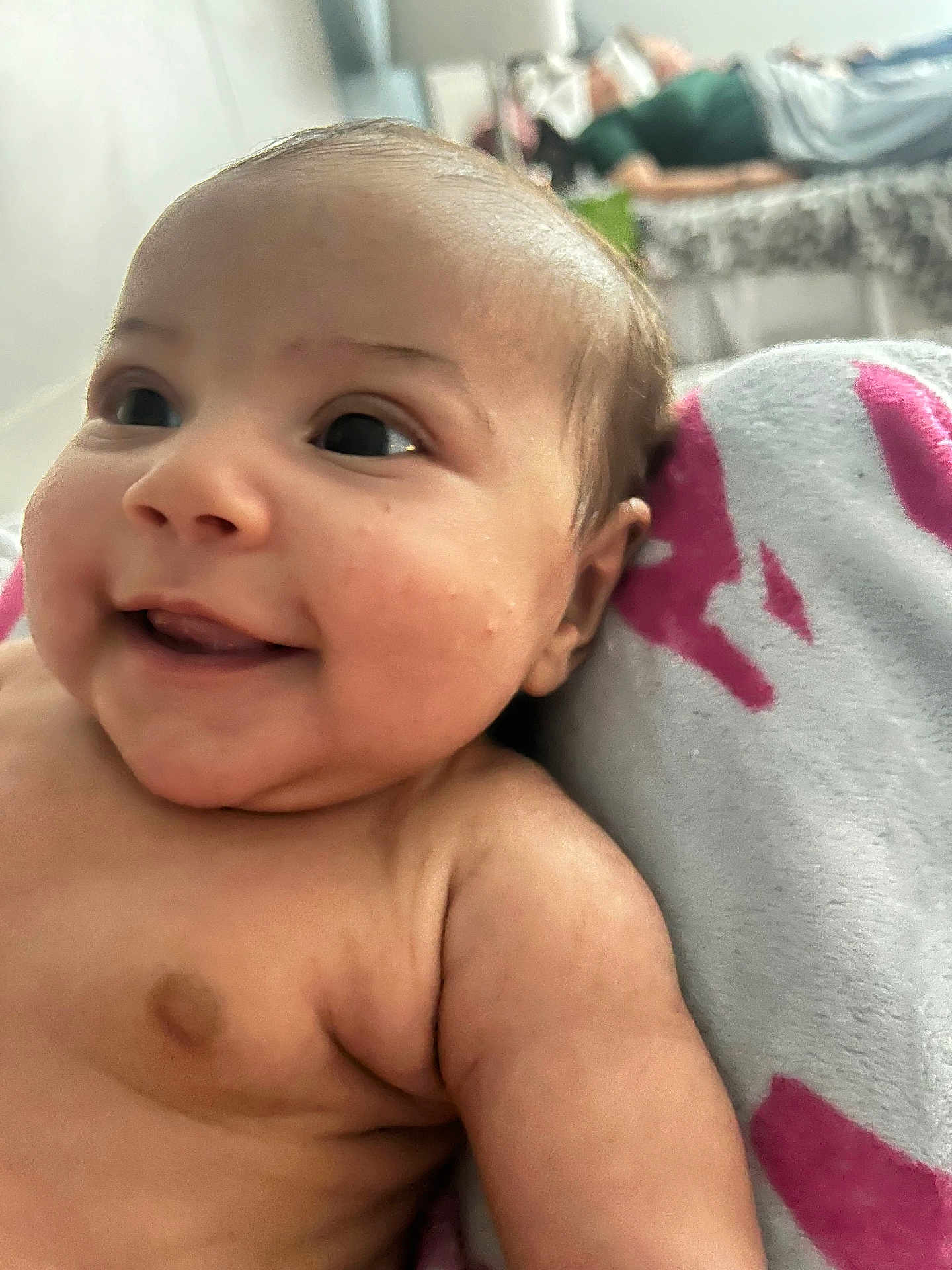 Iris joined the competition — help win amazing prizes! baby, infant, smile, face, skin, blanket, arm, cheek, indoors, bed, blurred_background, person, happy, cute, young_child, closeup, soft_texture, comfort, resting, warm