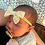baby, sleeping, pacifier, headband, lace, bow, infant, person, closeup, soft_lighting, blanket, arm, skin, newborn, resting, cozy, cute, child, indoor, portrait