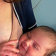 Iris is registered to the contest to win money with this photo: baby, infant, smiling, hand, face, skin, adult, clothing, blue_wall, closeup, portrait, happy, cute, newborn, person, tender, care, family, love, comfort