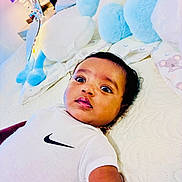 Amanuel joined the competition — help win amazing prizes! baby, bed, bedding, bedroom, blue, child, clothing, cozy, face, indoor, infant, lying_down, nike_shirt, pastel, photograph, plush_toy, portrait, stuffed_animal, white, wide_eyes