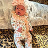Rhiannon is registered to the contest to win money with this photo: baby, infant, child, portrait, lying_down, awake, open_mouth, bow, headband, floral_outfit, romper, blanket, leopard_print, cushion, indoor, closeup, colorful, fashion, cute, photography