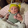 baby, infant, child, portrait, wide_eyed, indoor, blanket, bassinet, headscarf, yellow, green_outfit, white_blanket, lying_down, sitting, face, eyes, arms, wood_paneling, cozy, nursery
