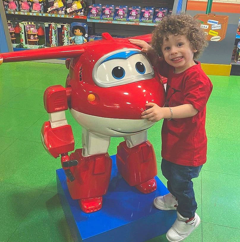 Luciano joined the competition — help win amazing prizes! blue, bookcase, boot, child, fictional_character, fun, games, happy, joy, leisure, machine, mascot, person, play, recreation, red, shelf, shorts, smile, t_shirt