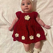 Eva Cataleya a rejoint le concours — aidez-le/la à gagner de superbes lots ! baby, infant, child, crocheted_dress, red_dress, headband, socks, white_blanket, flower_decorations, handmade_clothing, cute, portrait, laying_down, smiling, soft_texture, indoors, light_skin, happy, fashion, baby_fashion