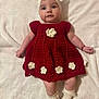 baby, infant, child, crocheted_dress, red_dress, headband, socks, white_blanket, flower_decorations, handmade_clothing, cute, portrait, laying_down, smiling, soft_texture, indoors, light_skin, happy, fashion, baby_fashion