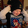 Joshua is registered to the contest to win money with this photo: child, boy, beanie, hat, mario_kart, shirt, smile, indoor, table, toys, glasses, person, room, playful, clothing, cozy, face, casual, young, expression