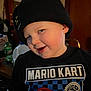 Joshua joined the competition — help win amazing prizes! child, toddler, boy, hat, beanie, black_hat, smile, indoor, shirt, mario_kart, graphic_tshirt, face, person, casual, cute, young_child, portrait, headwear, clothing, expression