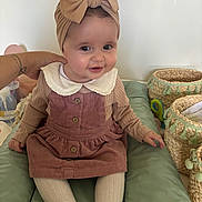Julia participe au concours pour gagner de l'argent avec cette photo : baby, child, smiling, headband, bow, dress, corduroy, tights, sitting, hand, basket, woven_basket, indoor, cushion, person, cute, infant, happy, portrait, clothing