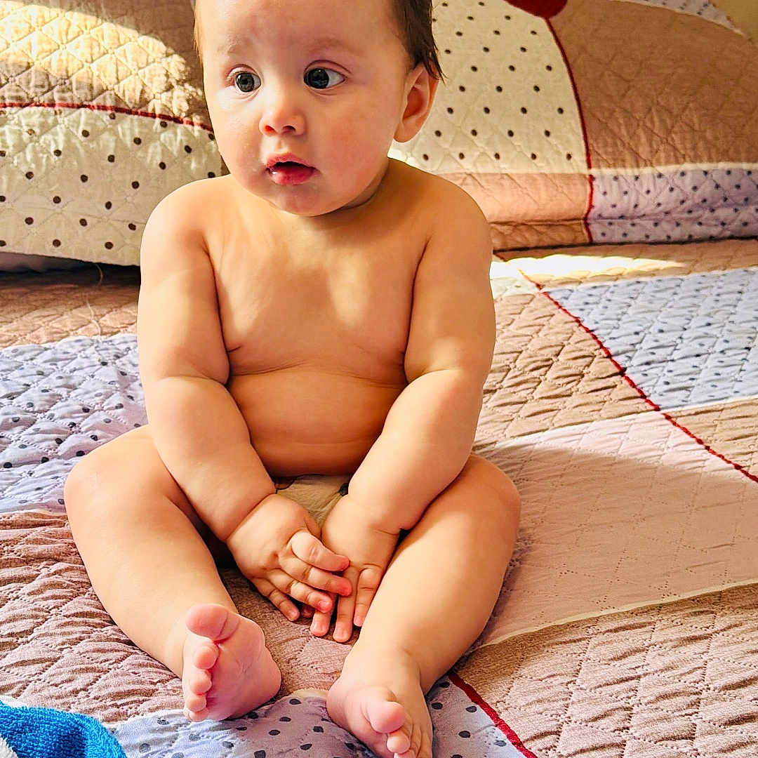 Wesly is registered to the contest to win money with this photo: baby, child, infant, bed, blanket, quilt, skin, barefoot, hands, feet, indoors, cute, curious, sitting, portrait, natural_light, home, soft, comfort, expression