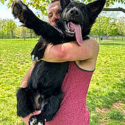 Scout joined the competition — help win amazing prizes! man, dog, black_dog, tongue_out, happy, outdoor, park, grass, tree, greenery, pet, holding, summer, sunny, casual_clothing, tank_top, playful, animal, canine, daytime