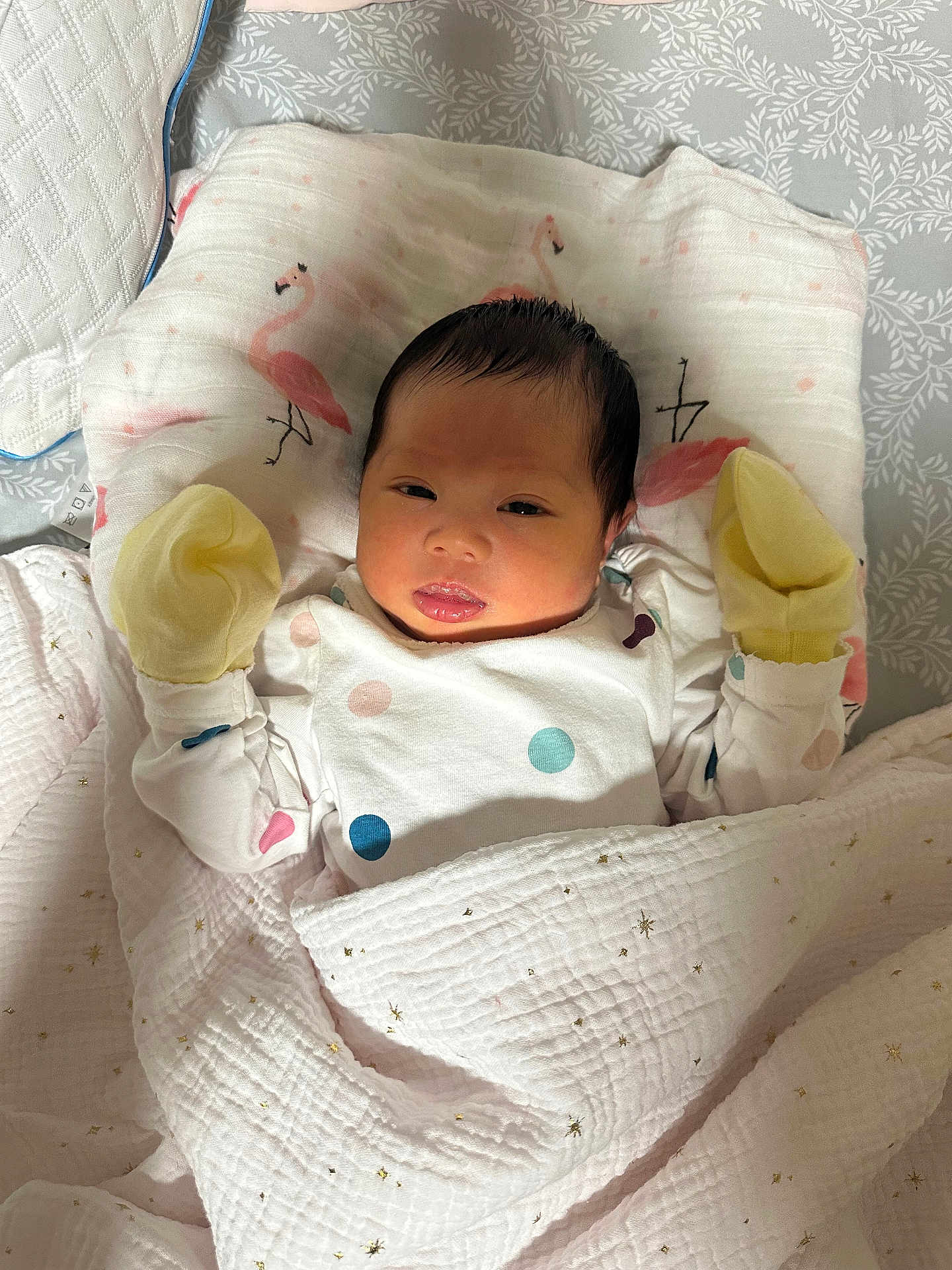 Esther joined the competition — help win amazing prizes! baby, infant, blanket, pillow, mittens, polka_dot, sleepwear, face, head, lying_down, cute, newborn, resting, indoors, soft_texture, patterned, flamingo, white, yellow, peaceful