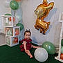 Inaya participe au concours pour gagner de l'argent avec cette photo : balloons, birthday, blocks, celebration, child, cute, decorations, deer_balloon, event, festive, floor, golden_balloon, green_carpet, indoors, party, red_dress, sitting, smiling, toddler, white_wall