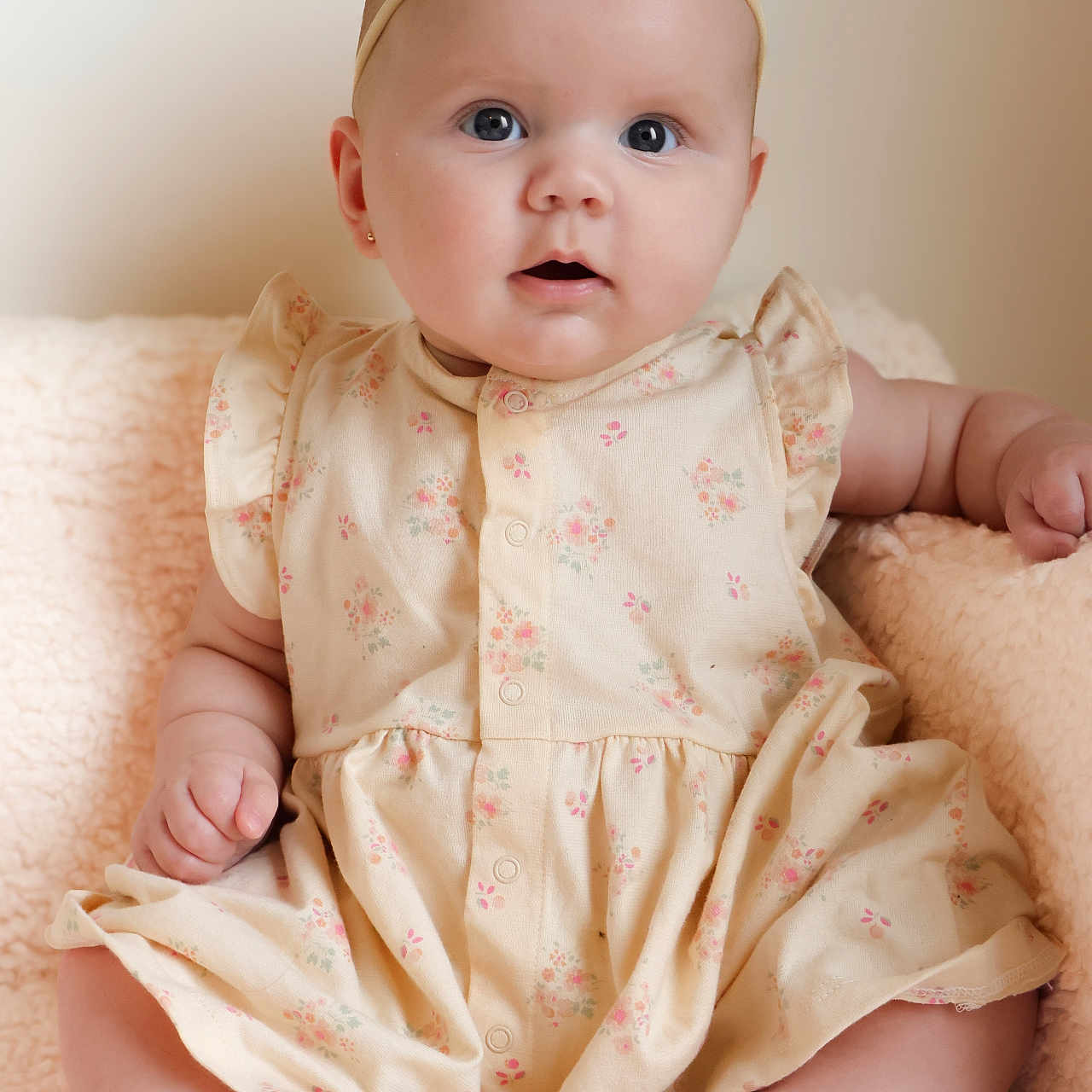 Ozzy joined the competition — help win amazing prizes! adorable, baby, child, comfortable, curious, cute, dress, expression, face, feet, floral_pattern, hands, headband, indoors, infant, pink_bow, portrait, sitting, skin, soft_blanket