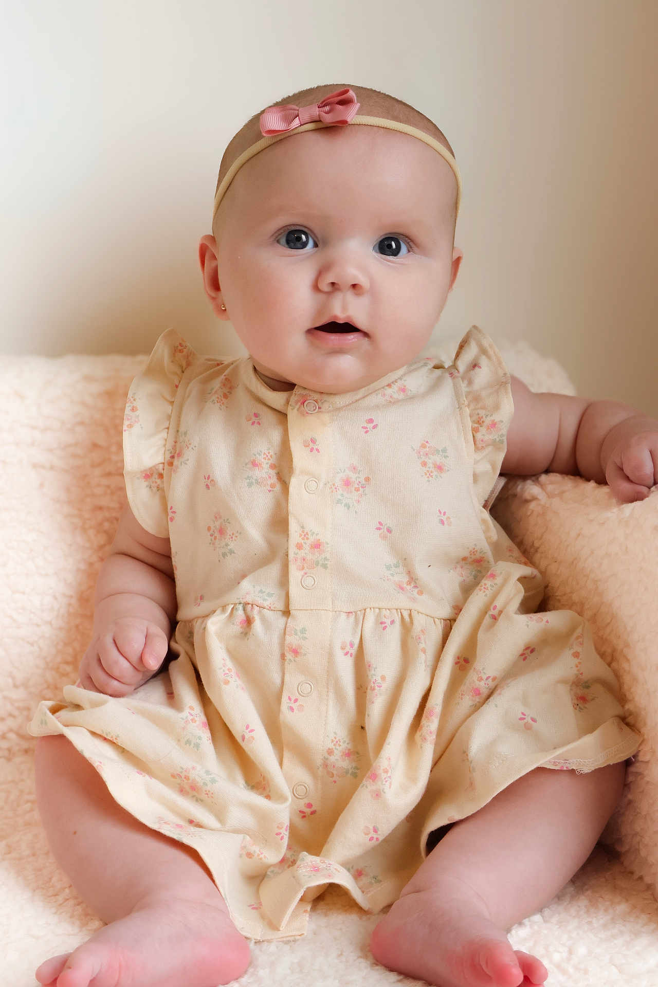Ozzy joined the competition — help win amazing prizes! baby, child, infant, dress, headband, pink_bow, cute, soft_blanket, sitting, portrait, indoors, skin, face, hands, feet, expression, curious, floral_pattern, comfortable, adorable