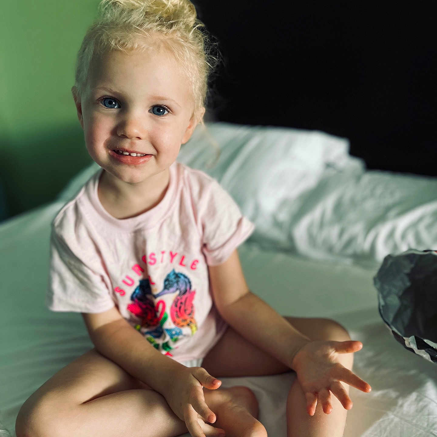 Lilly joined the competition — help win amazing prizes! baby, bed, bedroom, blonde, bodypart, clothing, face, finger, furniture, hair, hand, happy, head, indoors, person, photography, portrait, sitting, smile, t_shirt