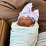 Saige joined the competition — help win amazing prizes! newborn, baby, sleeping, blanket, bow, hat, person, lap, clothing, cozy, indoor, soft, wrapped, cute, infant, resting, peaceful, child, portrait, headwear