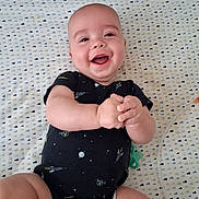 Kayden joined the competition — help win amazing prizes! baby, infant, smiling, happy, onesie, space_theme, crib, patterned_sheet, clasped_hands, lying_down, cute, child, person, skin, head, face, expression, indoors, baby_clothing, playful
