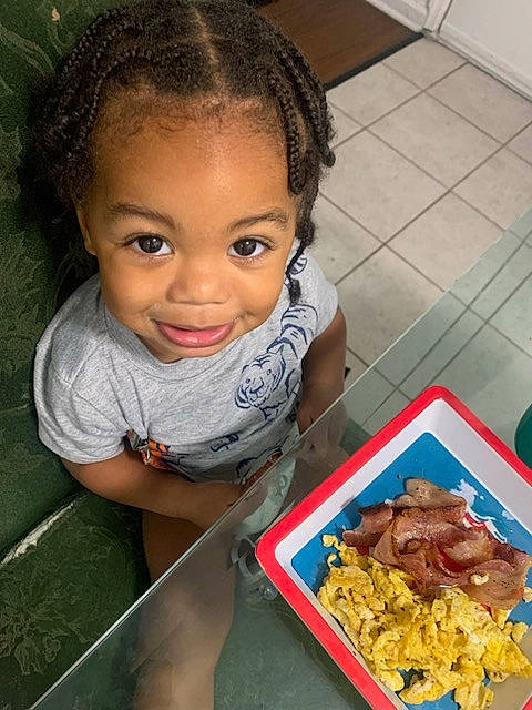 Karson is registered to the contest to win money with this photo: child, comfort_food, cuisine, dish, event, flooring, food, fun, happy, head, ingredient, junk_food, meat, organ, person, produce, recipe, smile, t_shirt, table