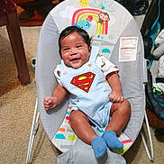 Kashton is registered to the contest to win money with this photo: baby, infant, smiling, romper, superman_logo, baby_bouncer, baby_seat, socks, rainbow, monkey, carpet, stroller, indoor, portrait, cute, happy, clothing, hair, furniture, living_room