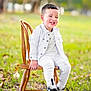 boy, casual, child, daylight, fashion, grass, happy, jacket, leaves, nature, outdoor, pants, portrait, seated, smiling, sneakers, toddler, white_clothing, wooden_chair, young