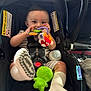 Jose is registered to the contest to win money with this photo: baby, car_seat, toy, bottle, socks, infant, child, smiling, cute, indoor, seatbelt, plush_toy, striped_clothing, footwear, playful, child_care, person, closeup, happy, comfort